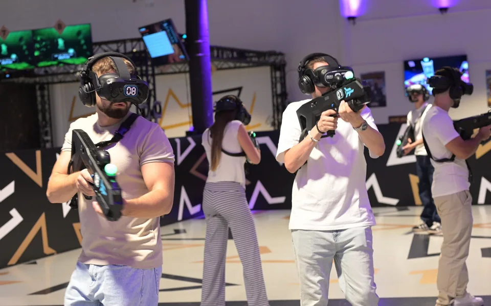 Gruppe spielt gemeinsam mit VR-Headsets und Controllern in der Arena